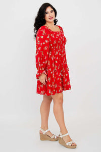 Side view of a model in a red ditsy print dress with ruffled long sleeves