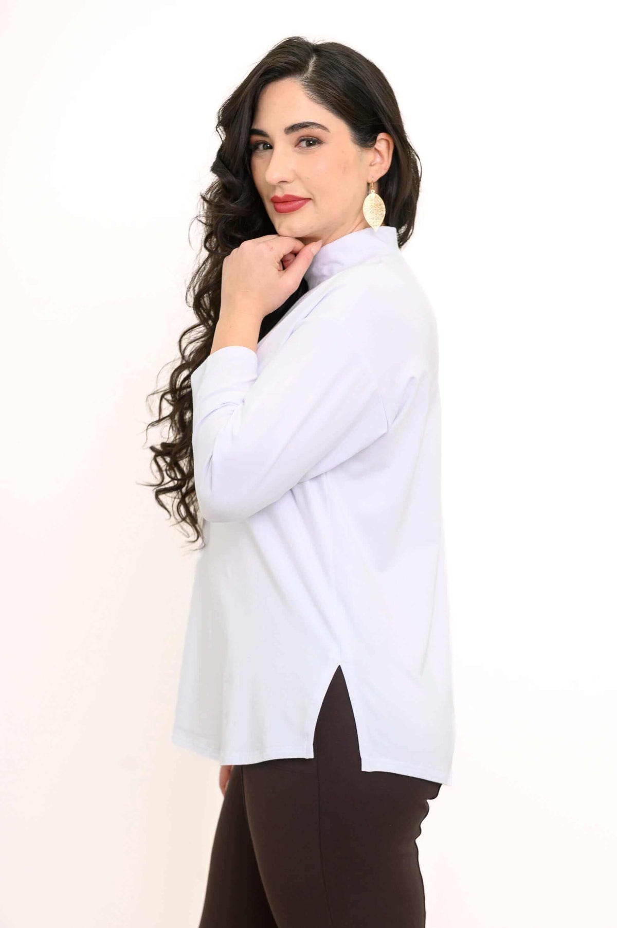 Side profile of a woman showcasing the white mock neck top's side slit