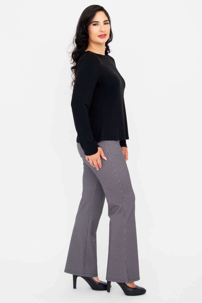Side profile of woman in black Mona boat neck long sleeve top and check pants
