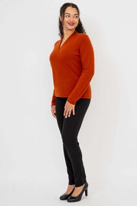 Side view of woman in rust surplice cashmere sweater and black pants