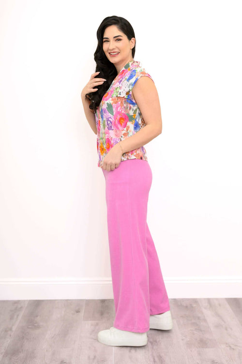 Side profile of a woman modeling a colorful floral top and pink pants