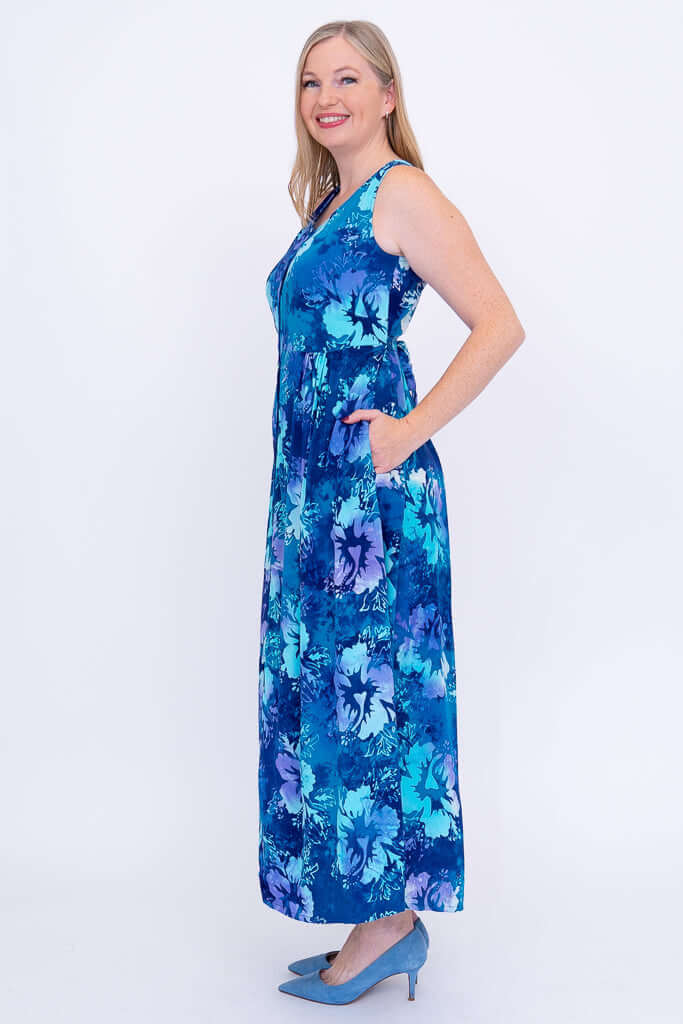 Side view of a woman in a blue floral sleeveless maxi dress with her hand in the pocket