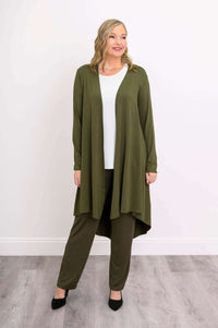 Model looking sideways in olive green high-low duster and pants, hand at side