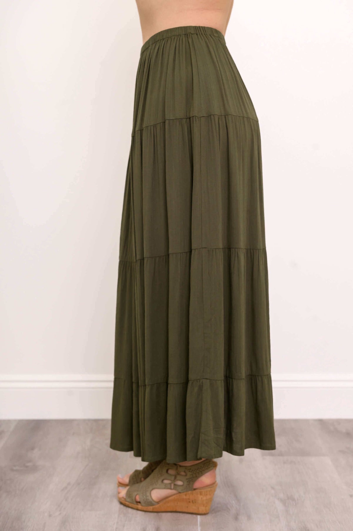 Side view of olive green tiered maxi skirt showing flowing tiers and wedge sandals