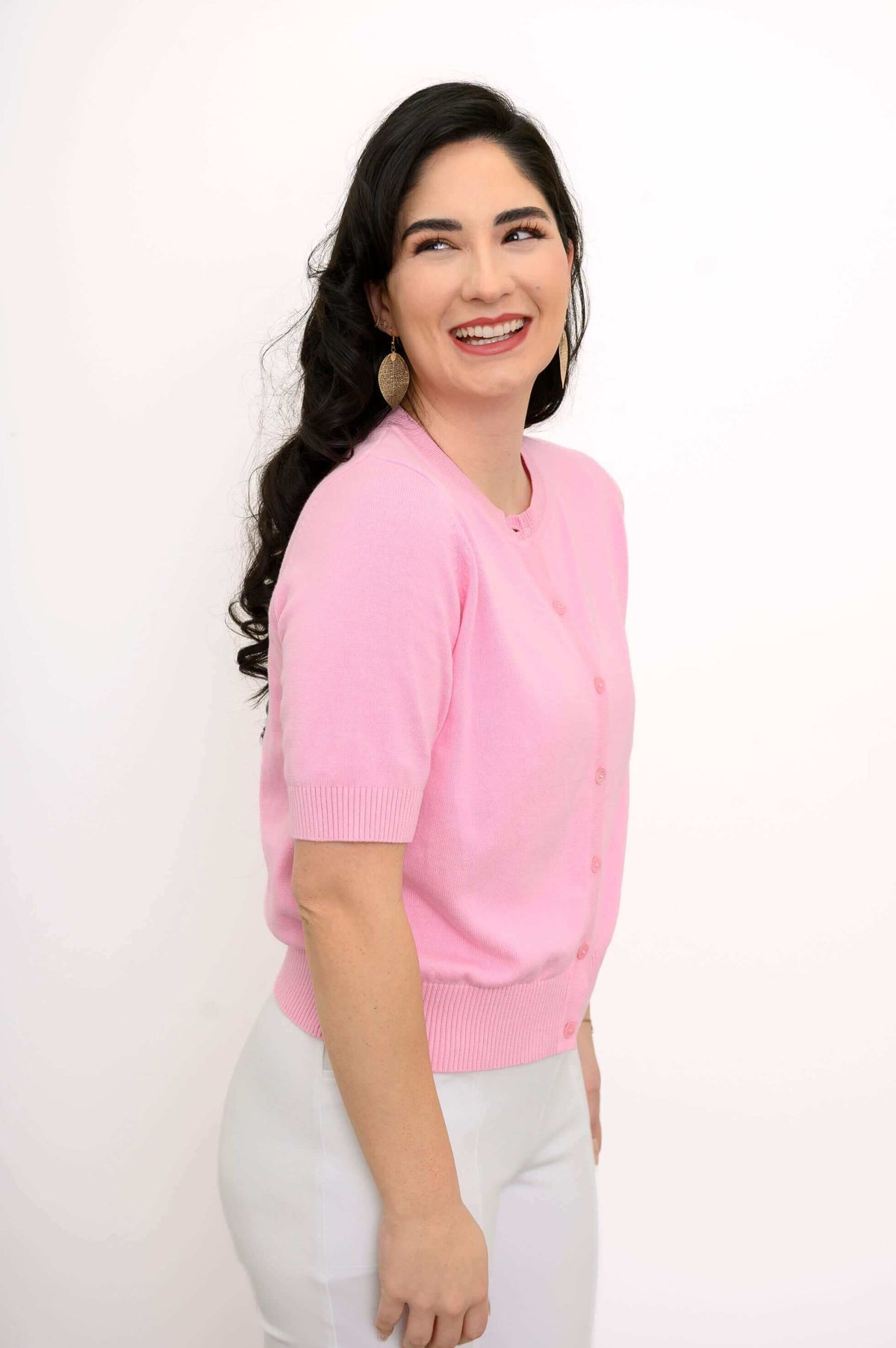Side view of woman smiling in a pink short-sleeve button-up cardigan