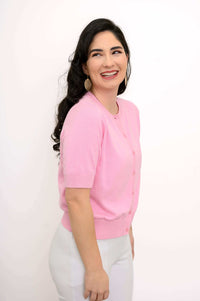 Side view of woman smiling in a pink short-sleeve button-up cardigan