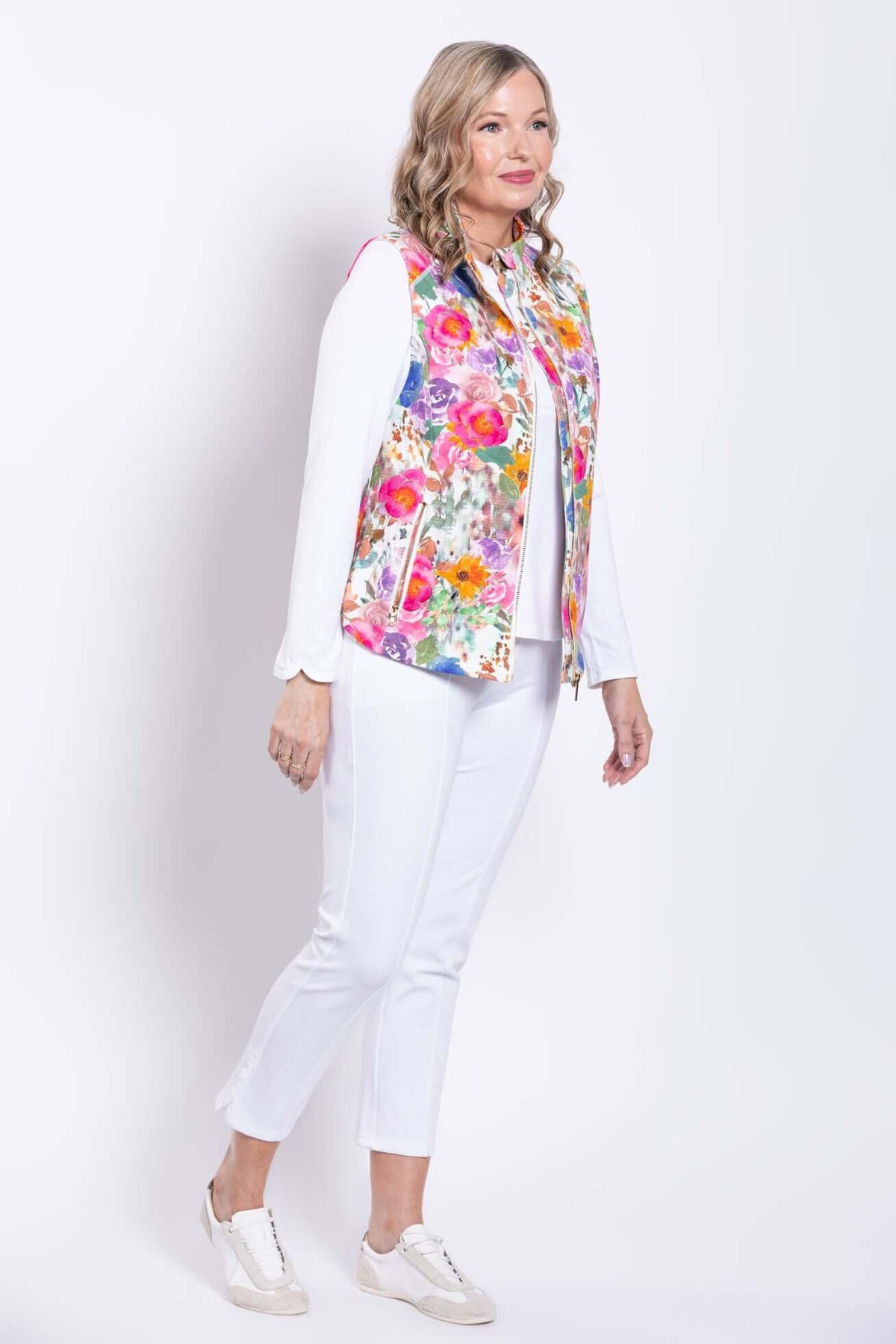 Side view of woman in a pink floral print vest and white pants