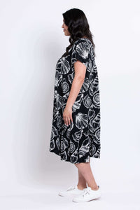 Side view of a woman in a black and white shell print midi dress