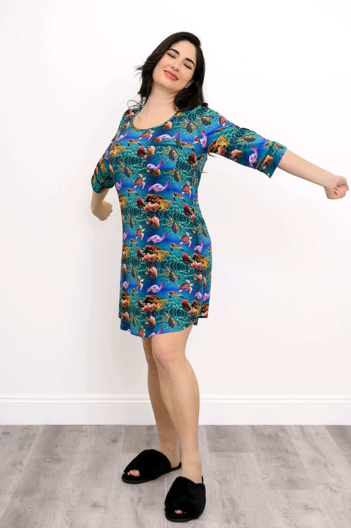 Woman stretching her arms while wearing bamboo coral reef print sleepshirt, side view