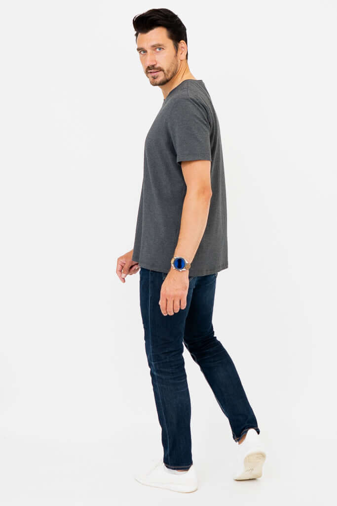 Side view of man in dark grey V-neck T-shirt and jeans looking back
