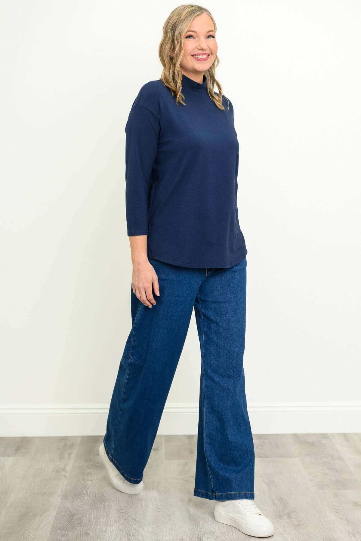 Side view of woman in navy mock neck bamboo top and blue jeans