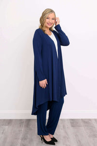 Woman posing sideways in navy blue duster cardigan with matching trousers and black shoes