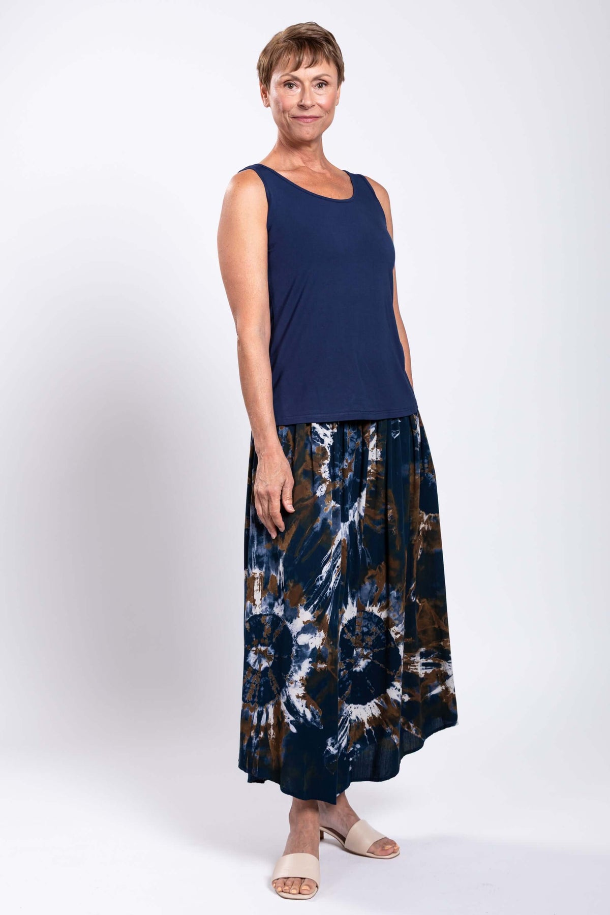 Model angled to the side in navy top and tie dye batik midi skirt, showing skirt details