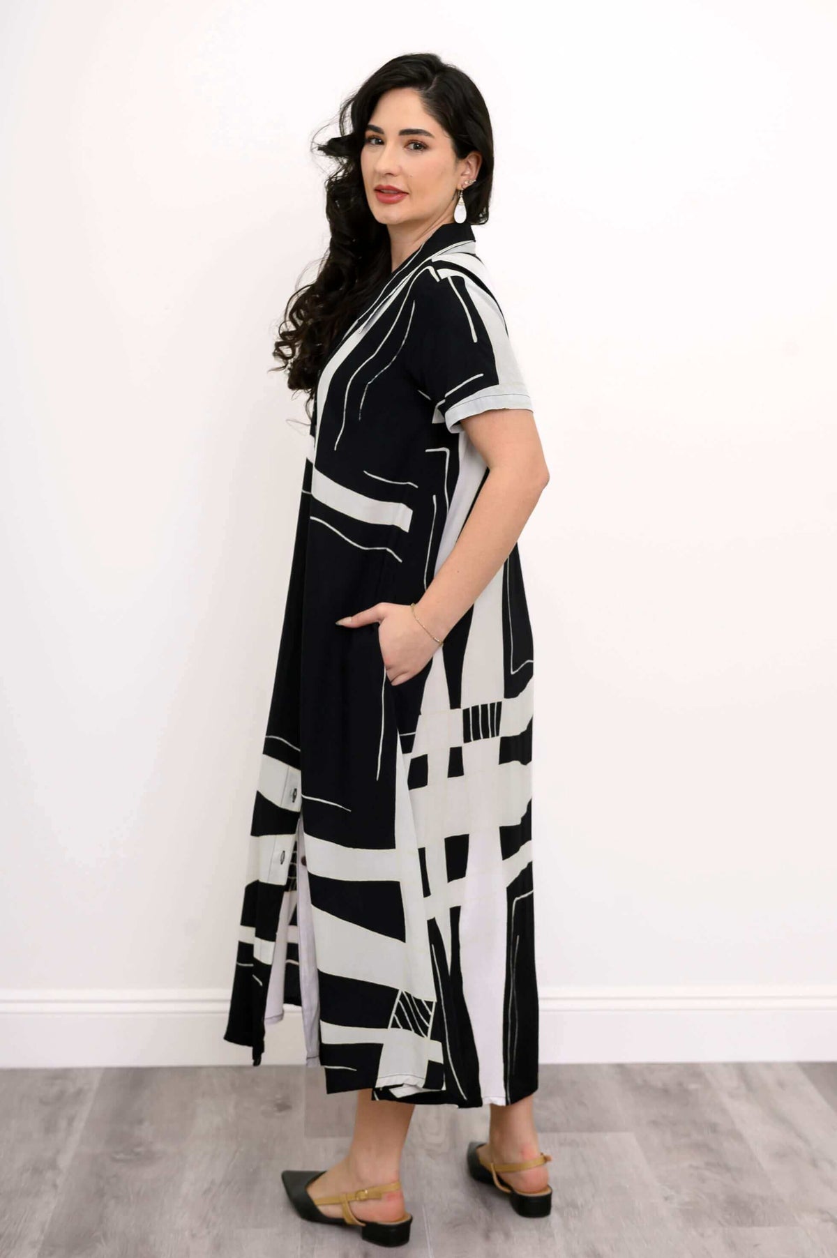 Side view of woman wearing black and white geometric A-line shirt dress with short sleeves