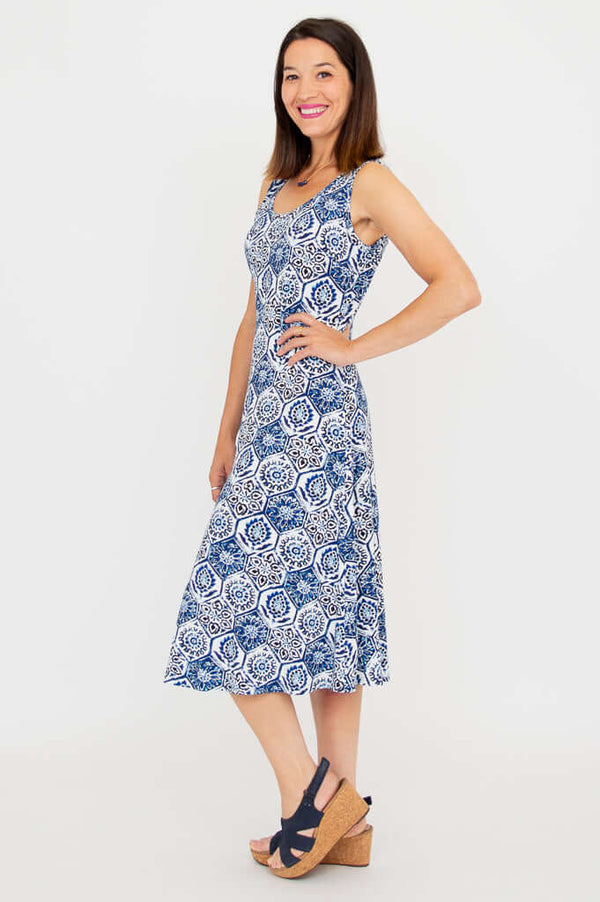 Woman in a sleeveless blue and white patterned tank dress, side profile view