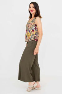 Side profile of a woman in a patterned tank top and wide leg green pants