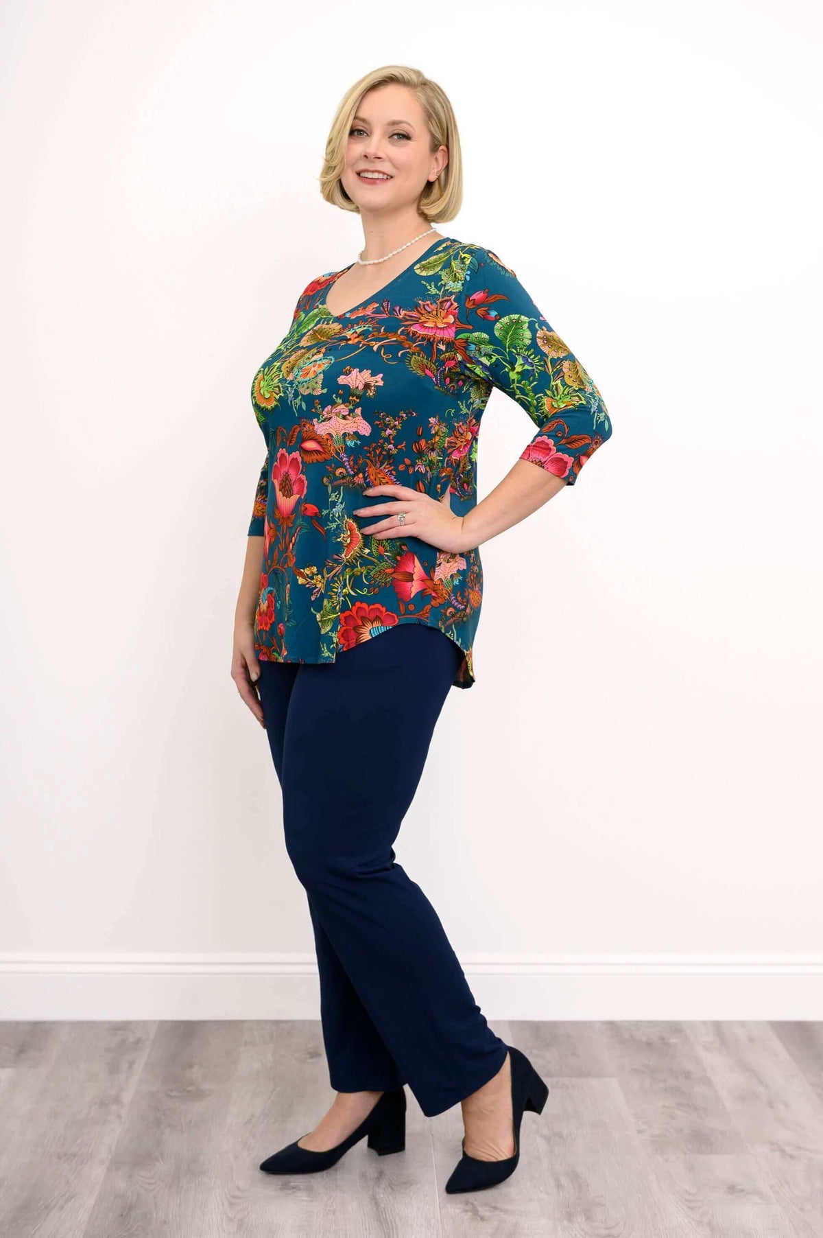 Side view of woman in Jackie V Neck teal bamboo top with colorful floral pattern