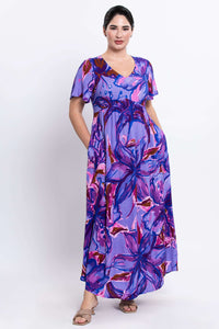 Side view of a woman in a purple floral maxi dress with pockets and flutter sleeves