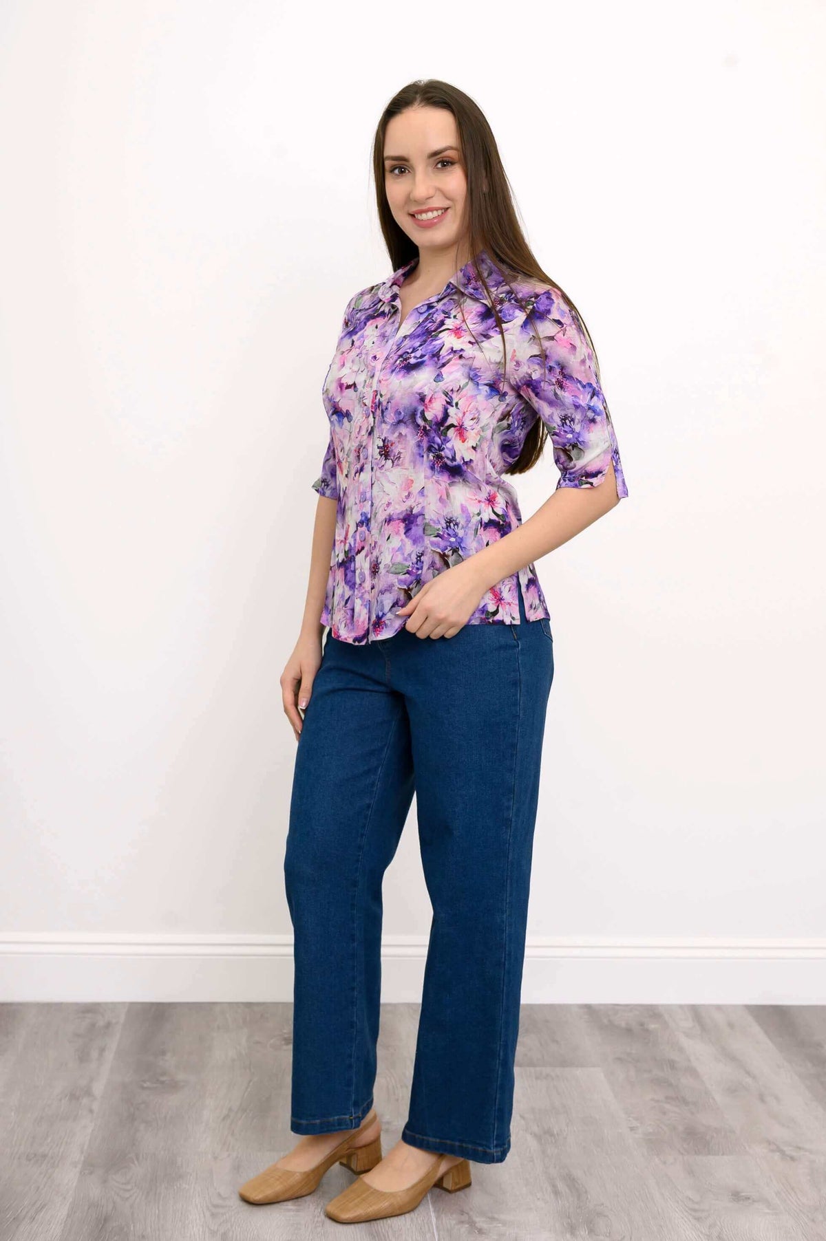 Side angled view of woman in purple floral blouse and blue jeans