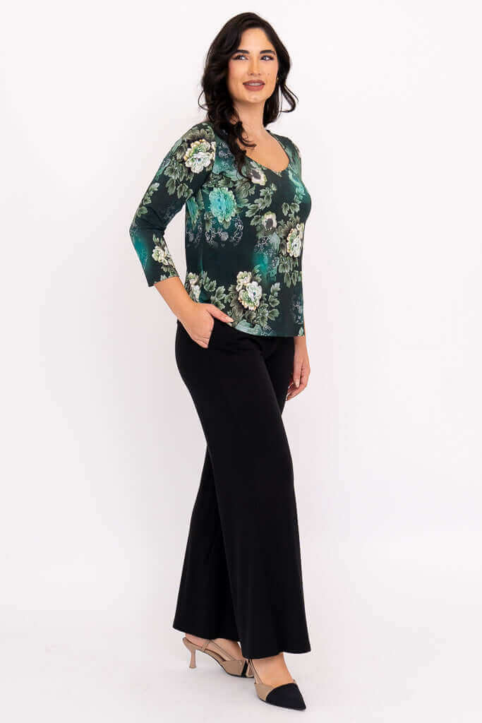 Side view of model in green floral 3/4 sleeve top paired with wide leg black pants