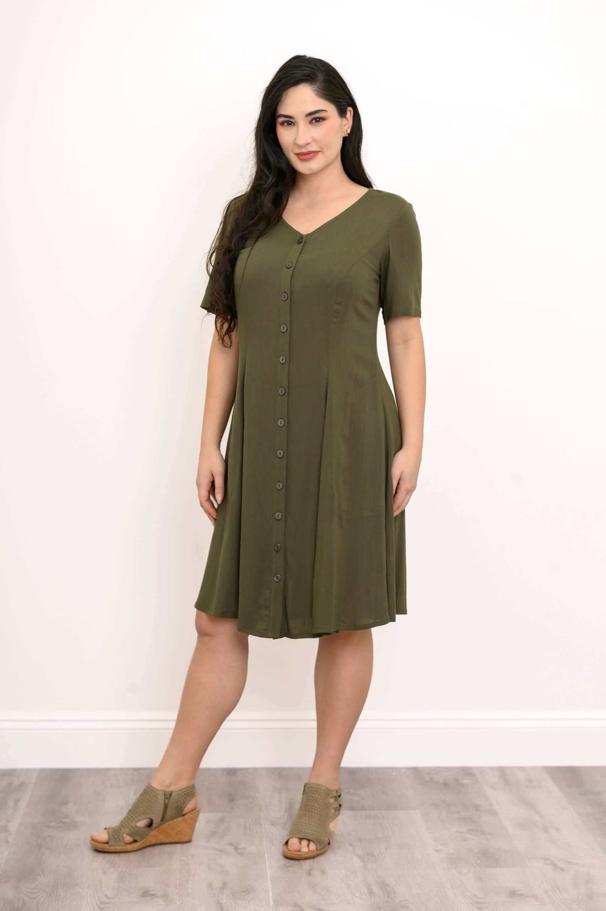 Front angled view of woman in olive green knee-length dress with button-down front
