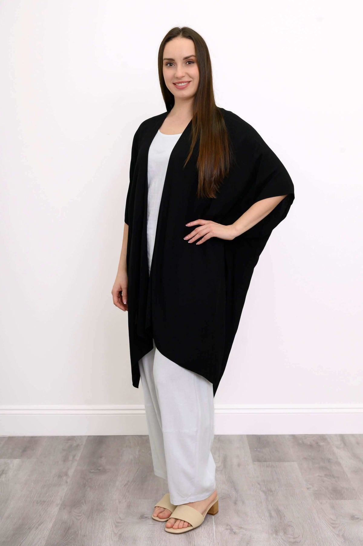 Side angle of woman modeling black Darcy kimono wrap and white pants