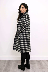 Side view of model in black and white checkered long coat with hands in pockets