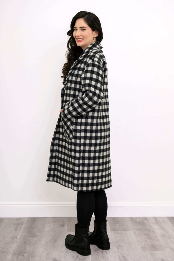 Side view of model in black and white checkered long coat with hands in pockets