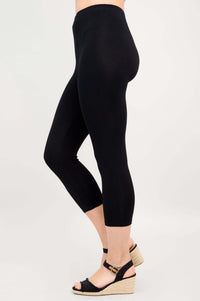 Side profile of a person wearing black capri leggings with wedge sandals