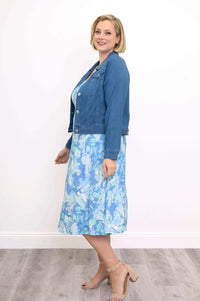 Woman in blue abstract tank dress paired with a denim jacket, side view