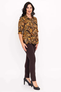 Side view of model showcasing golden leaf blouse and brown pants outfit