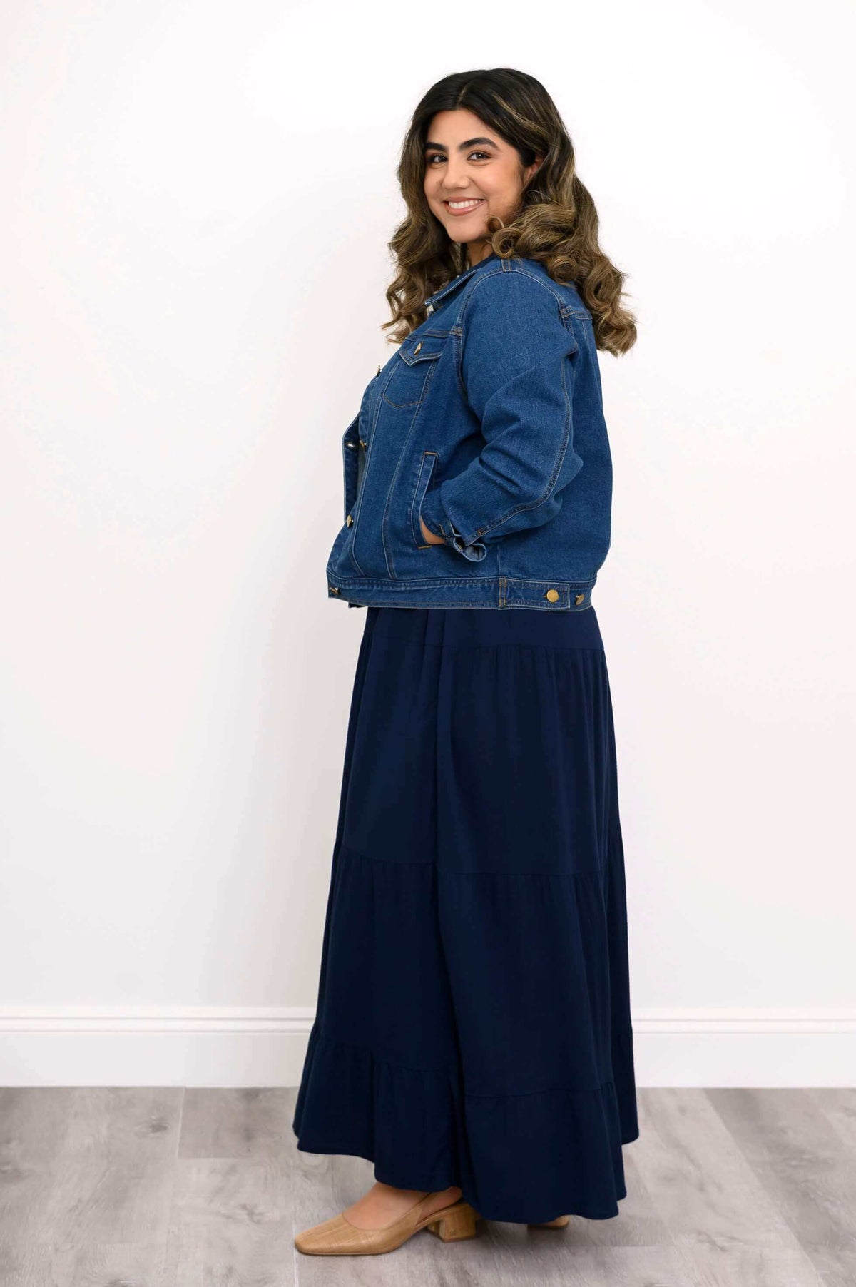 Side view of model wearing denim jacket and navy Roma tiered maxi skirt