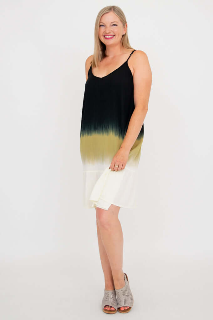 Side view of woman in ombre sleeveless dress holding the hem