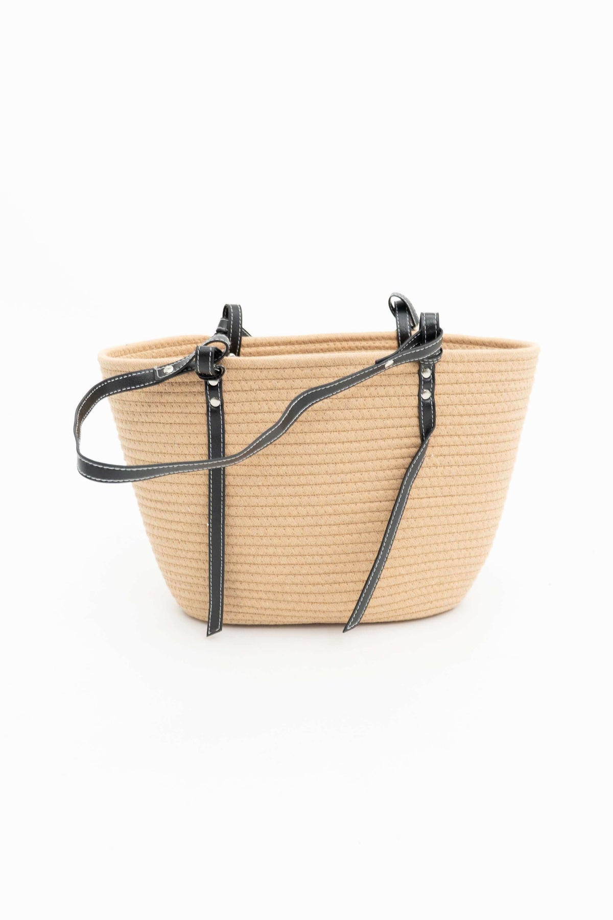 Side profile of tan cotton tote bag with black handles on white surface