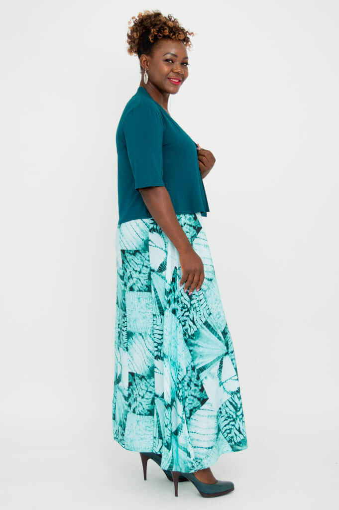 Side view of model in teal cropped bamboo jacket paired with turquoise patterned dress