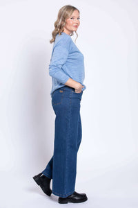 Model showing side profile of wide leg denim jeans with blue top