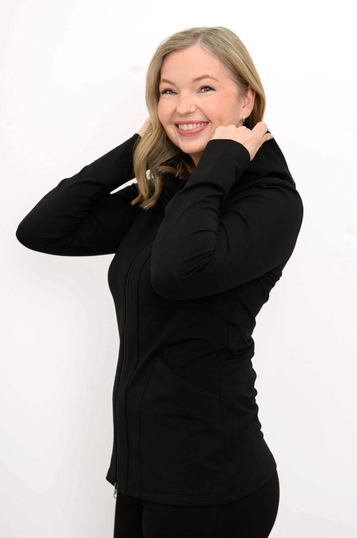 Woman side view adjusting the hood of a black fitted hoodie jacket