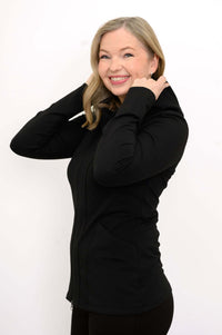 Woman side view adjusting the hood of a black fitted hoodie jacket