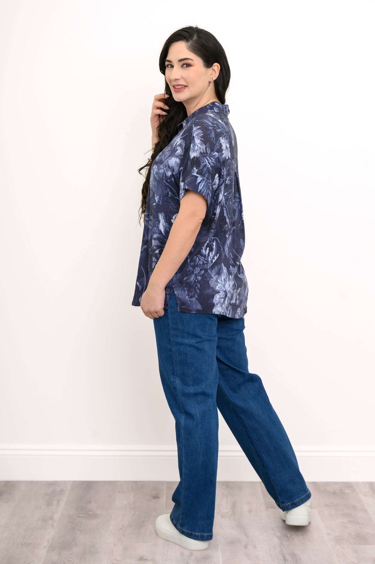 Side view of woman in blue floral blouse with dolman sleeves and blue jeans