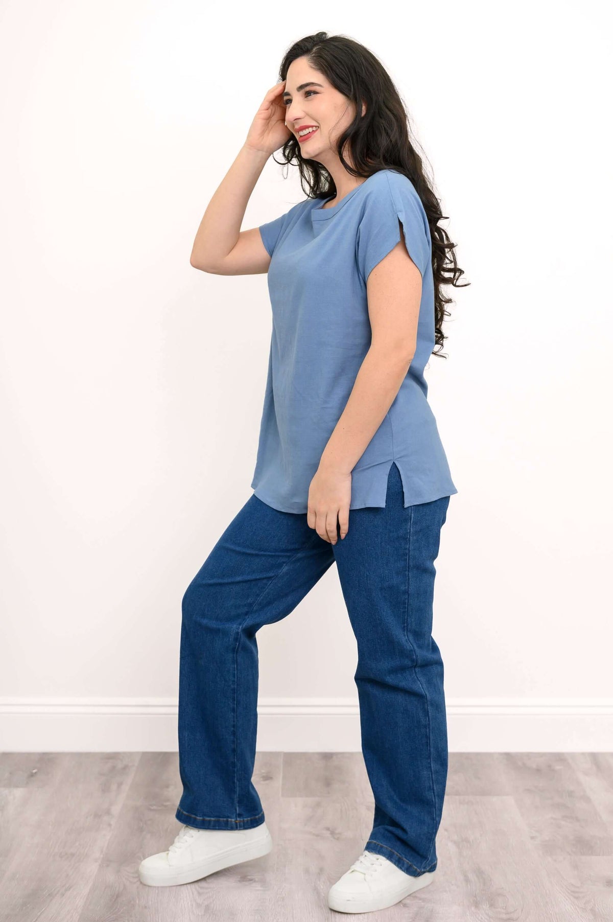 Side view of woman in light blue dolman tee and blue jeans