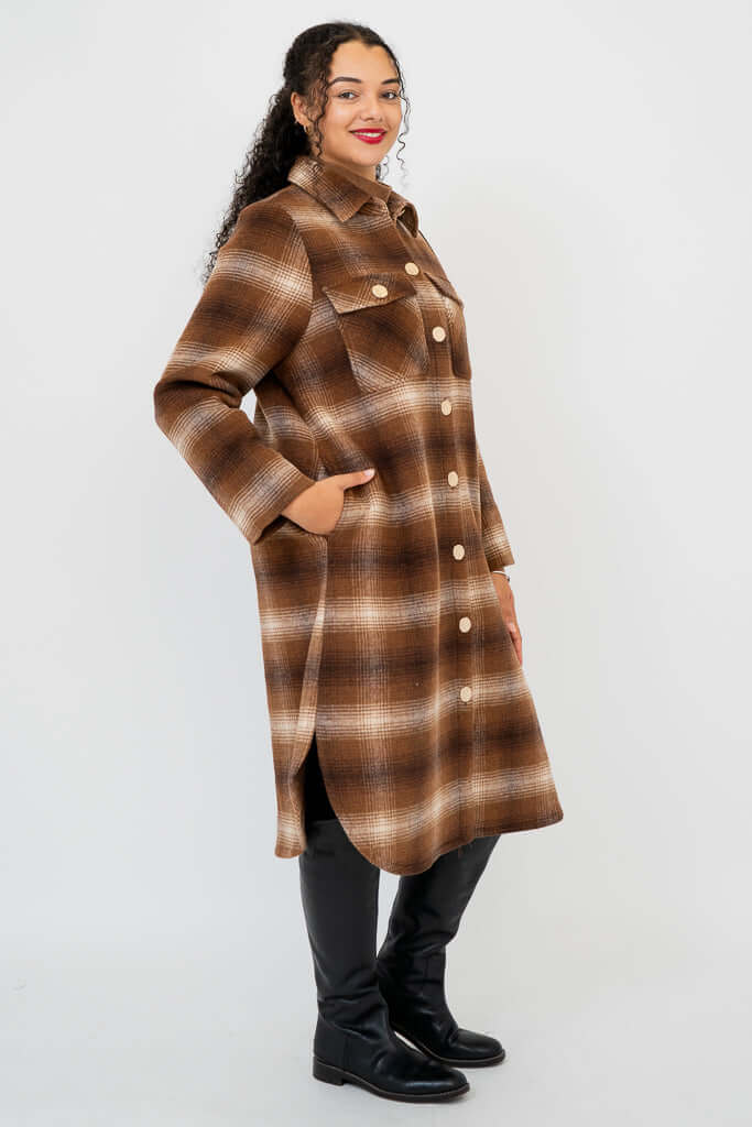 Side view of model with hand in inseam pocket wearing brown plaid coat