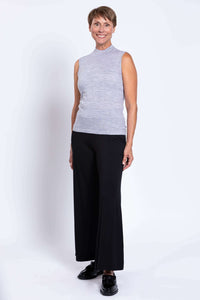 Side view of a woman in a sleeveless light grey Merino wool sweater and black pants
