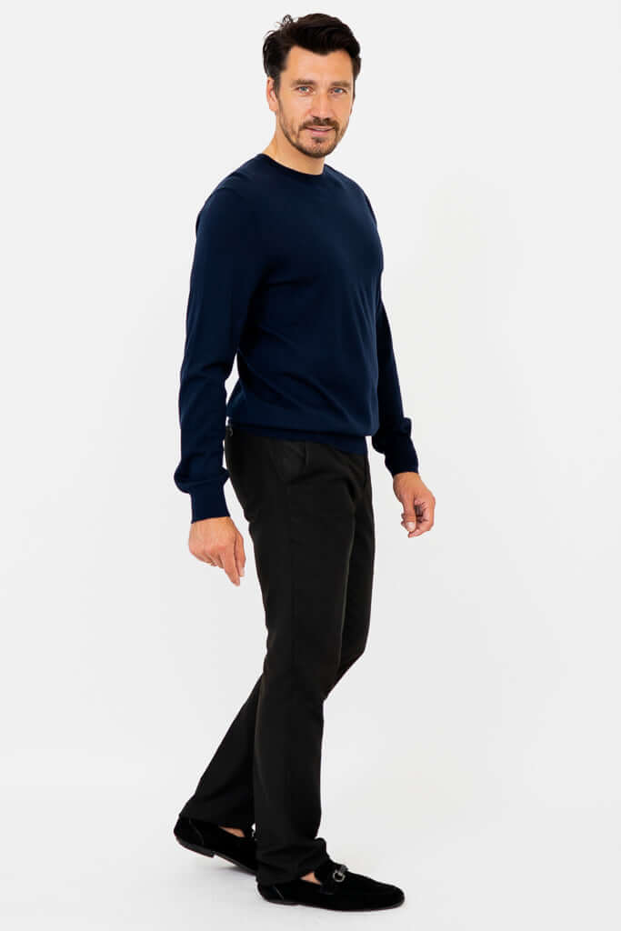 Side angle of man in navy merino wool sweater and black pants, smiling