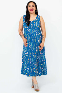 Woman smiling in a blue sleeveless floral maxi dress, facing forward