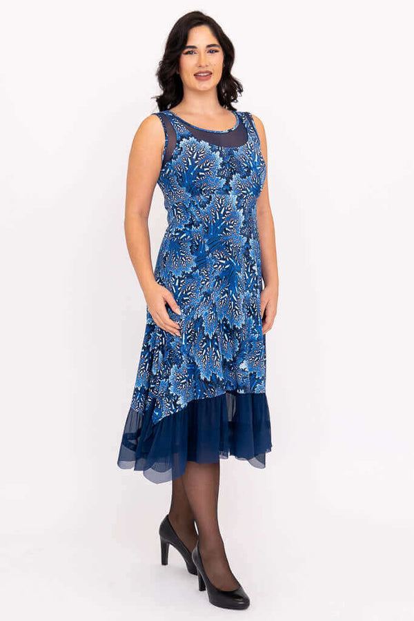 Woman wearing a sleeveless blue floral dress with mesh underlay and hemline
