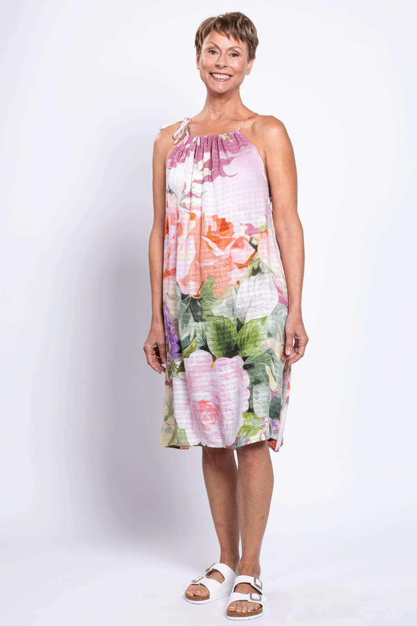 Woman wearing a sleeveless, knee-length floral beach dress with adjustable tie shoulder