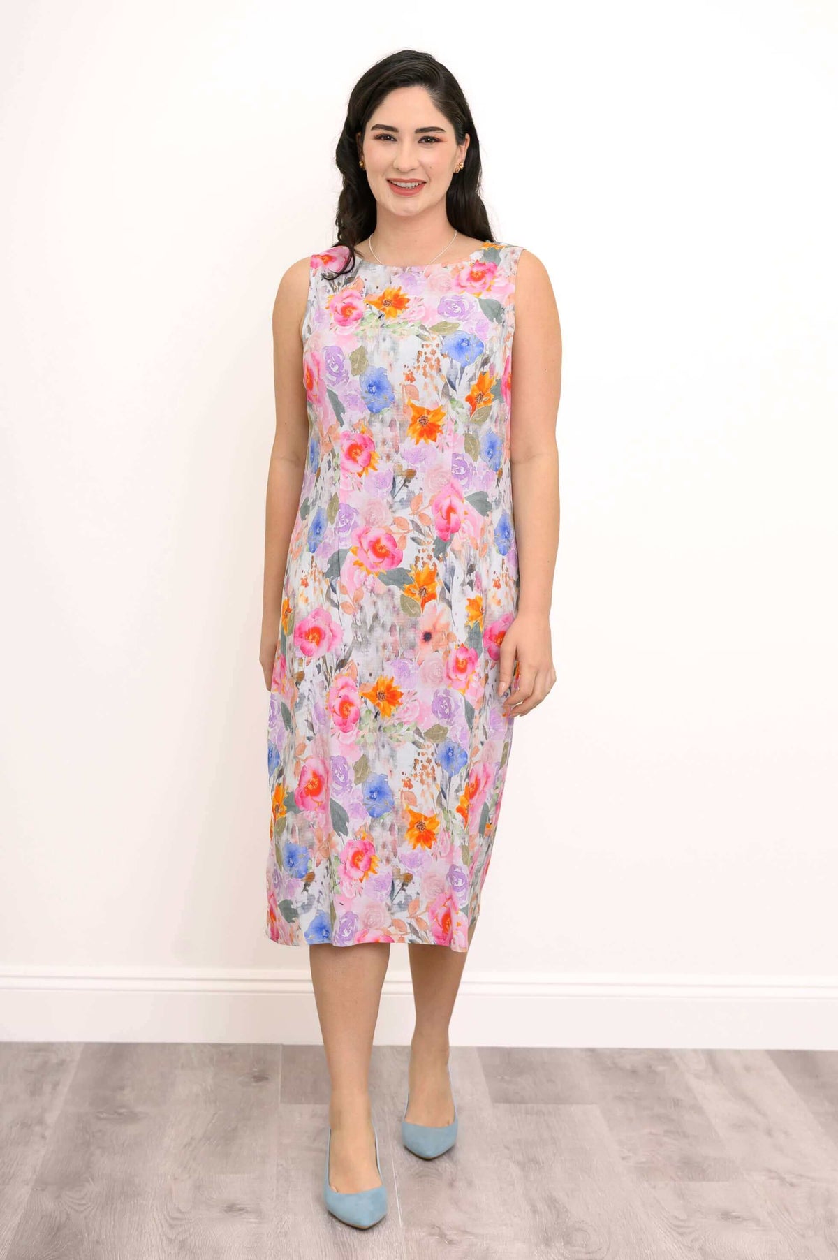 Woman wearing sleeveless floral shift dress with blue heels