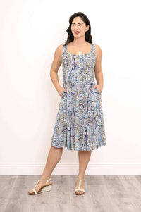 Woman wearing a sleeveless paisley print A-line dress with pockets, front view