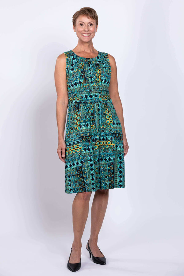 Woman wearing a sleeveless turquoise mosaic print dress, front view