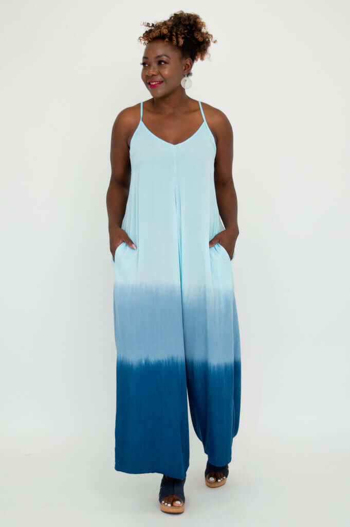 Model with hands in pockets, turned slightly, in an adjustable strap blue ombre jumpsuit